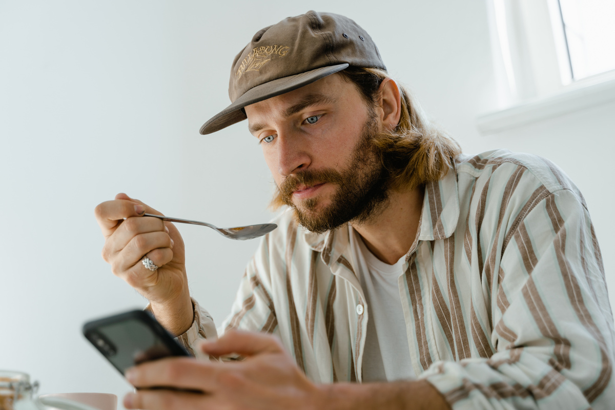 Man in White Dress Shirt Wearing Brown Hat Holding Black Smartphone